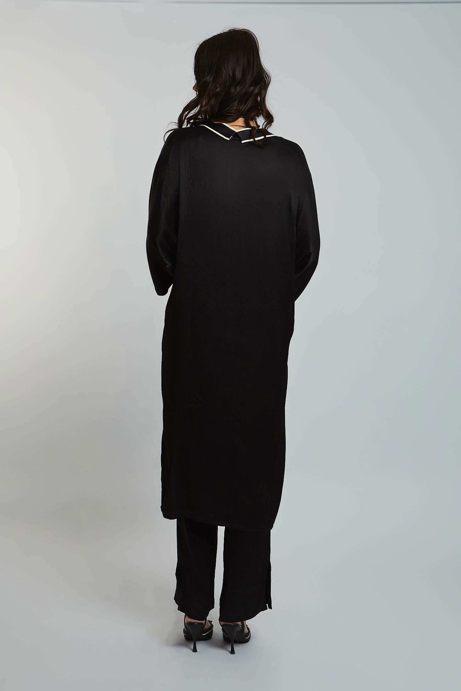 Woman in black long-sleeve tunic and pants set, back view, on plain background