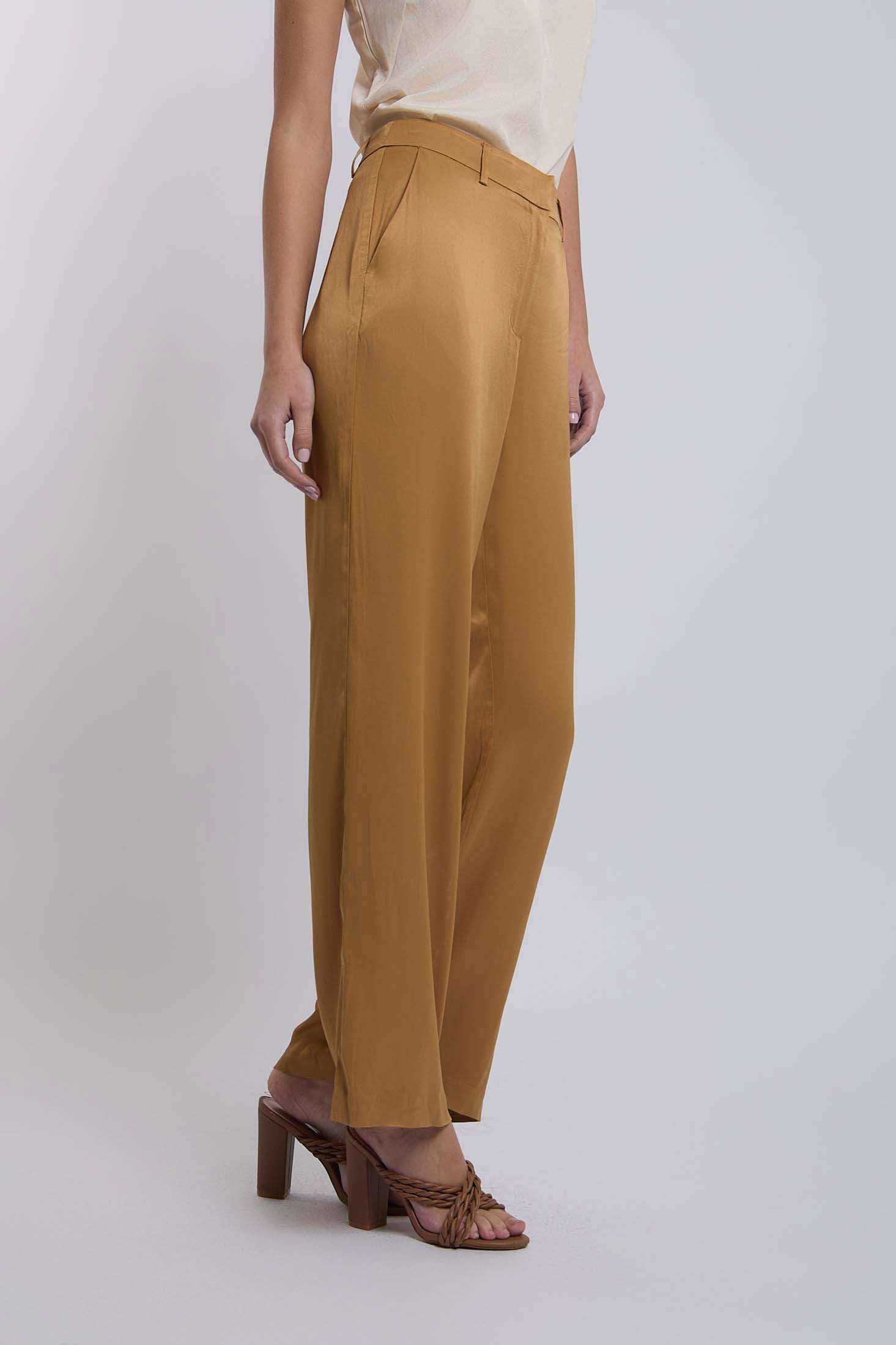Woman wearing mustard wide-leg trousers with side pockets and tan heeled sandals