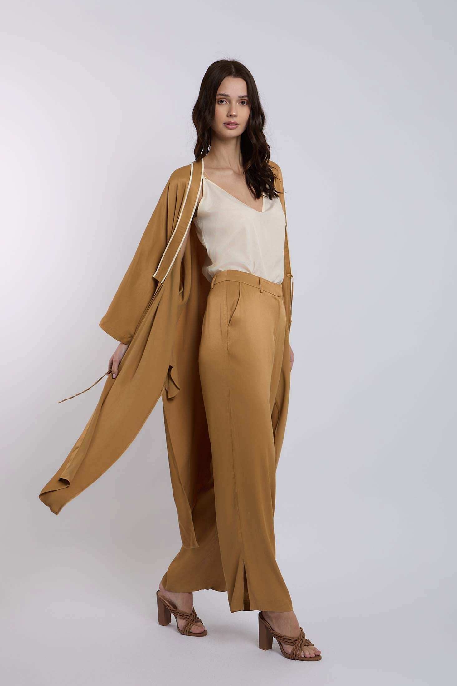 Woman wearing tan wide-leg pants, matching long coat, and cream blouse, fashion outfit